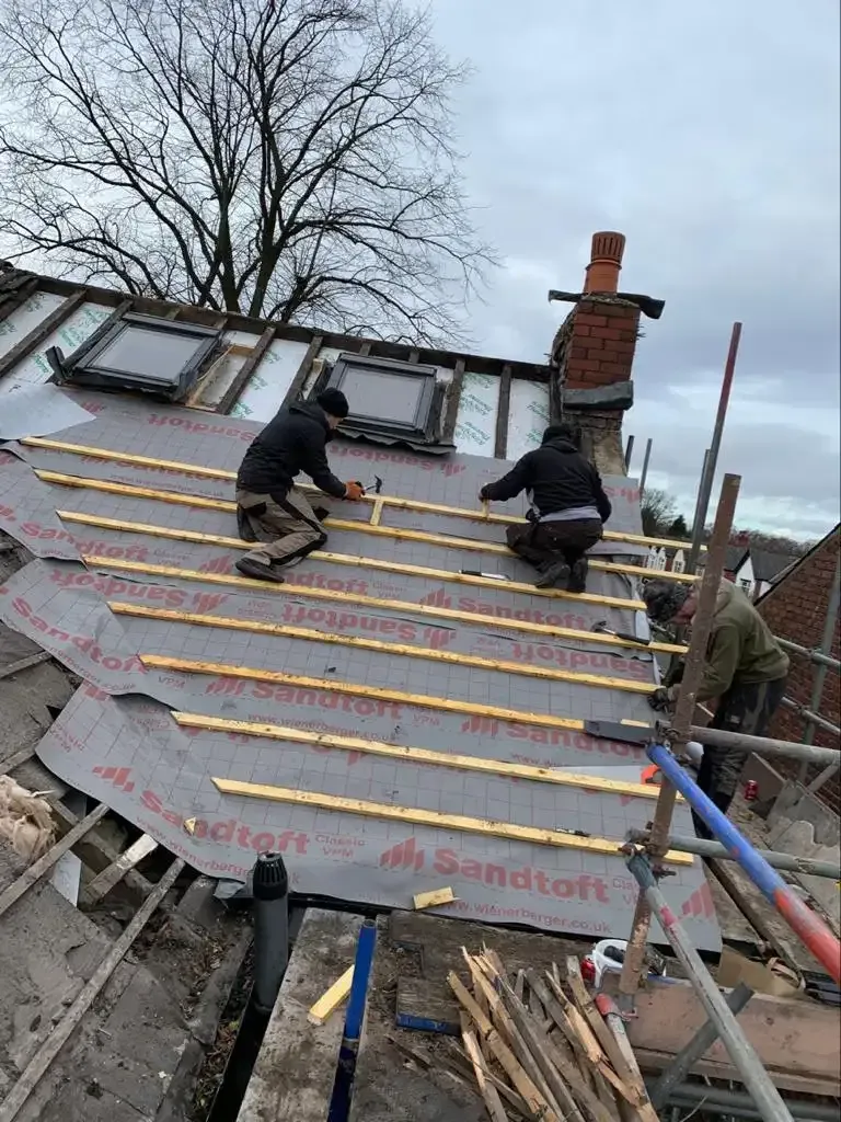 Roofers installing felt and battens on a pitched roof