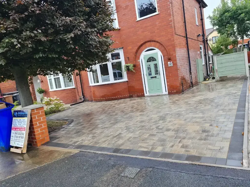 Newly laid block paving driveway in front of a red brick house with a green front door.