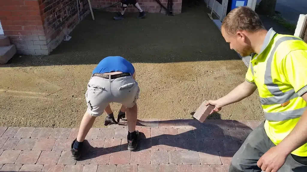 Workers installing block paving bricks for a driveway in Manchester.