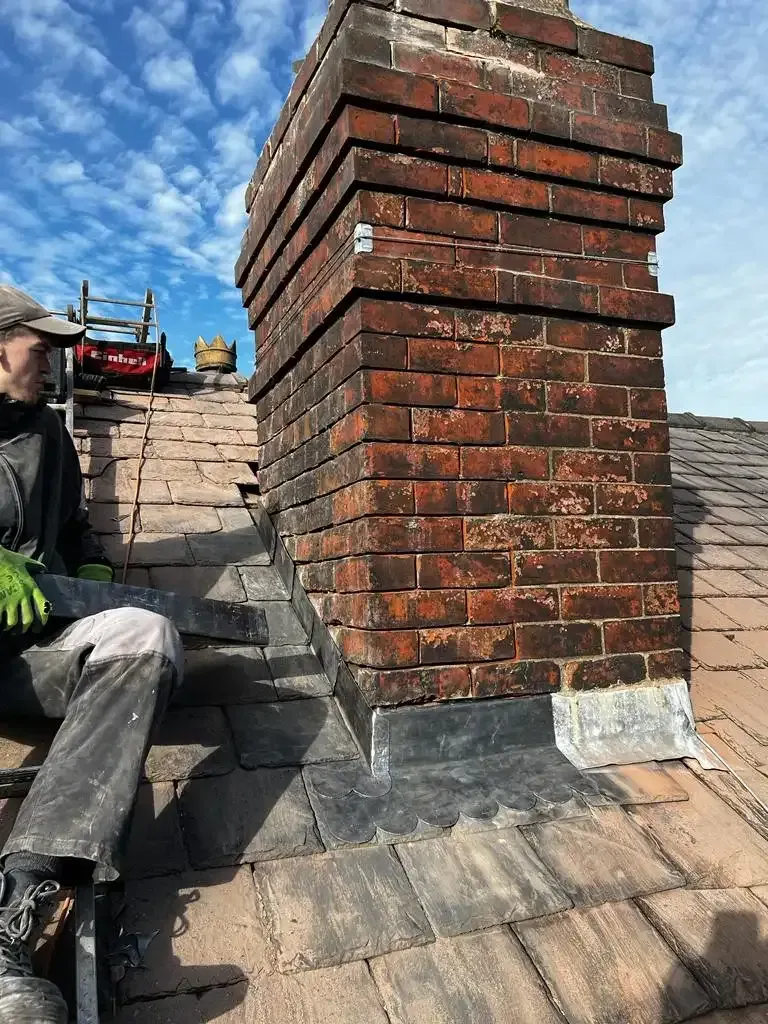 Professional chimney repair work on a red brick chimney and tiled roof, including lead flashing.