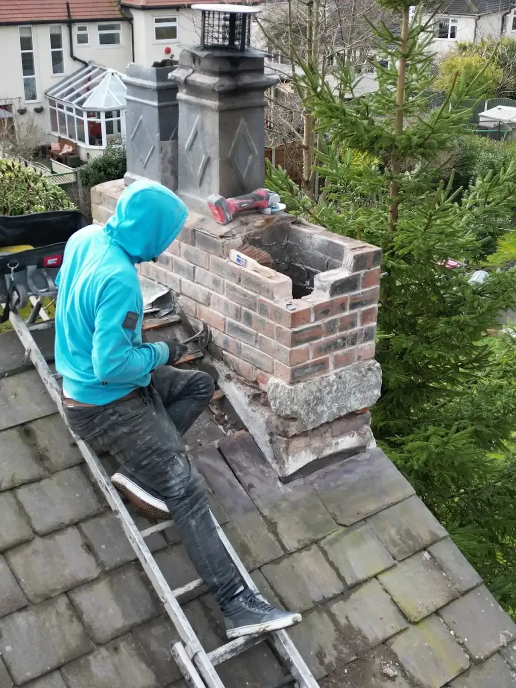 Roofer carrying out chimney repair work on a tiled roof.