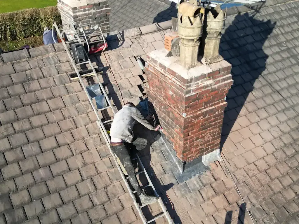 Expert roofer repairing a brick chimney on a tiled roof.