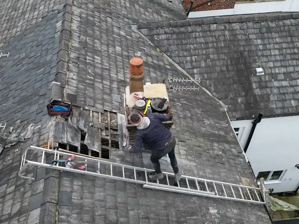 Roofer repairing a slate tile roof and chimney in Manchester